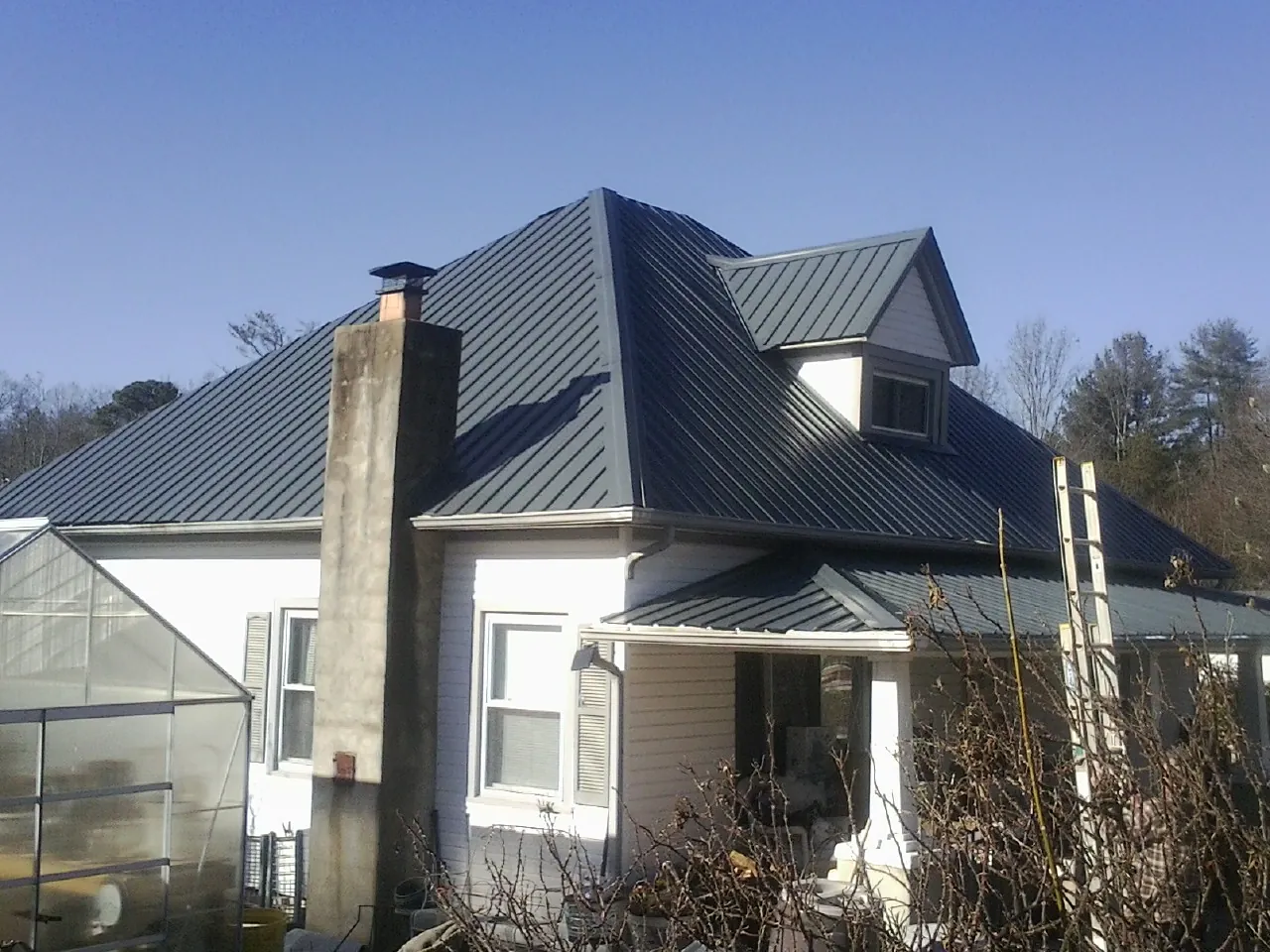 Dark blue standing seam metal roof on a white farmhouse with dormer — Slate & Tile Roof Repair by Roofing Brothers in Alhambra