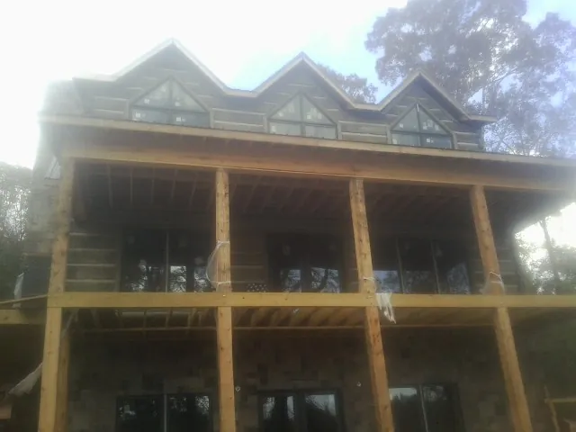 Dormers and porch framing on a large log home under construction — Roof Coating work by our crew in Alhambra