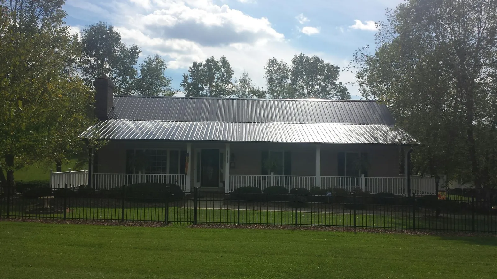 Gray metal roof on a brick ranch with a full width front porch — Gutter Guard Installation work by our crew in Alhambra