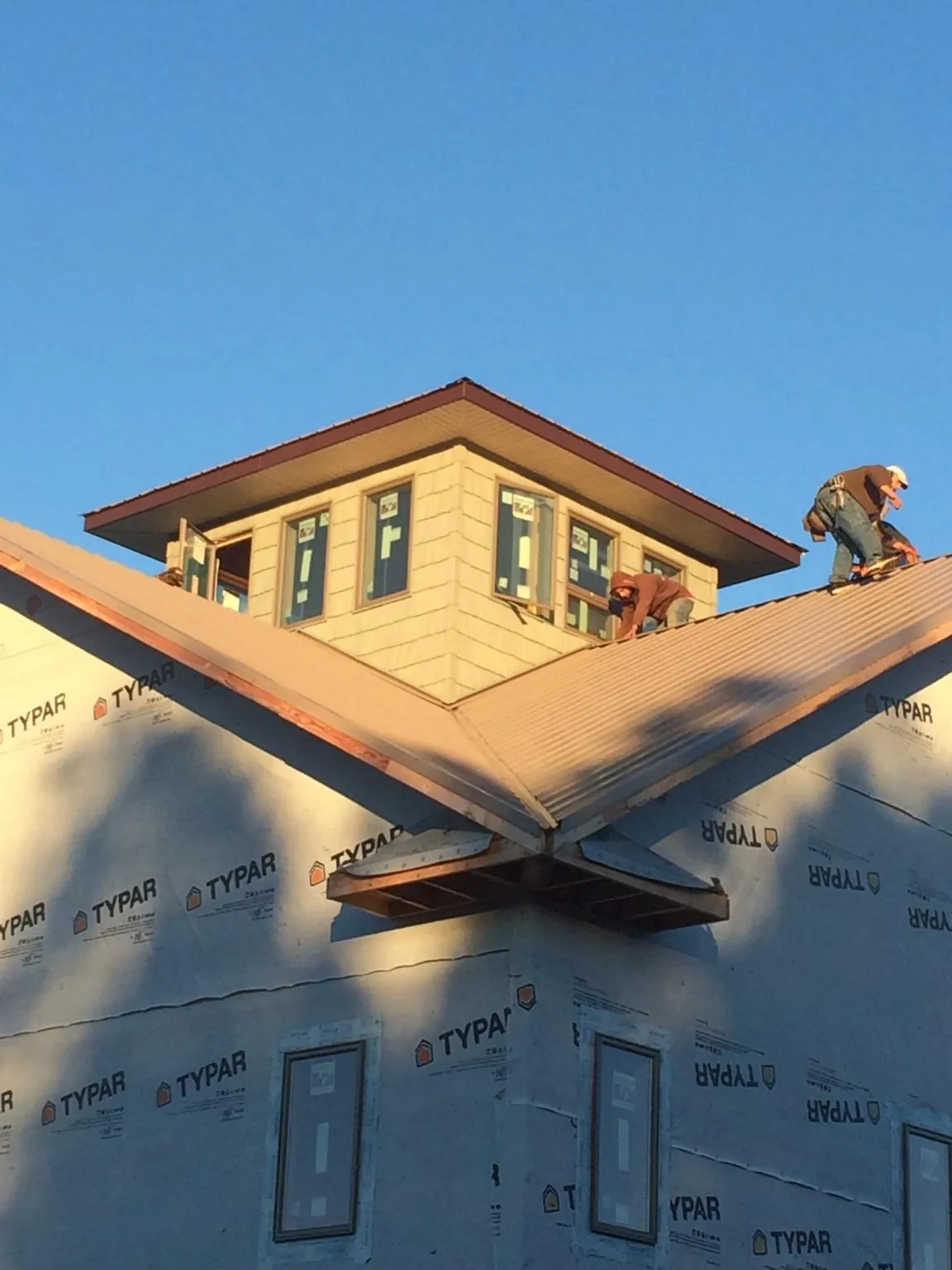 Roofers working around a rooftop cupola on a new metal roof at sunset — Roof Waterproofing in Alhambra by Roofing Brothers